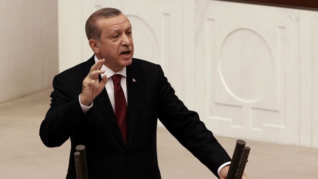 Purtret da Erdogan davant il pult da pledader en il parlament. 