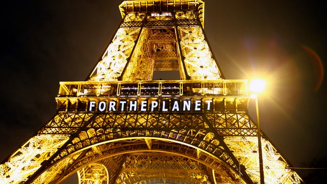 Purtret da la Tur Eiffel cun scrit si «per il planet» per engles.