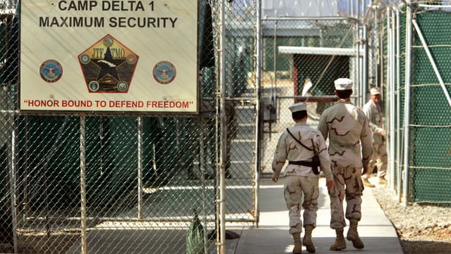 Trais survegliaders da praschun passan giatters da serrada en la praschun da Guantanamo