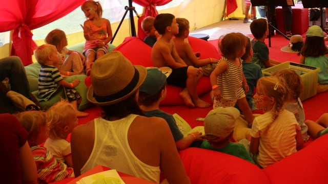 Uffants sesan sin gronds satgs cotschens e verds e taidlan las istorgias durant la festa d'uffants a Laax Uffants sesan sin gronds satgs cotschens e verds e taidlan las istorgias durant la festa d'uffants a Laax