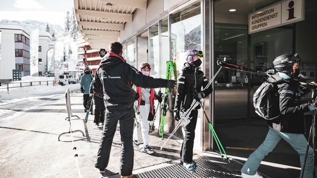 turists da skis cun mascrinas tar la staziun a val da las pendicularas d'Arosa