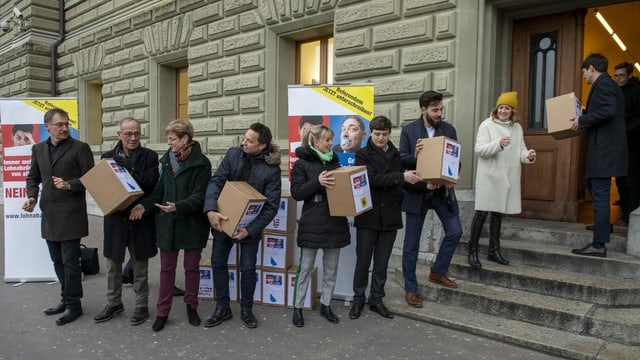 Glieud avant la chasa federala a Berna portan pachets cun suttascripziuns