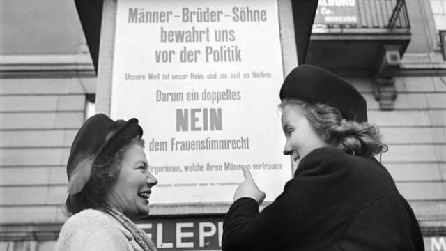 Duos dunnas il 1950 davant in placat cun l'inscripziun "Männer - Brüder - Söhne, bewahrt uns vor der Politik. Nein zum Fraunestimmrecht"