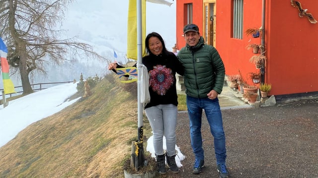 Silvio e Dawa Capaul avant lur chasa cun la bandiera dal tibet 