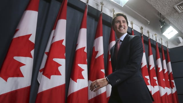 Il nov primminister dal Canada avant bandieras dal Canada.