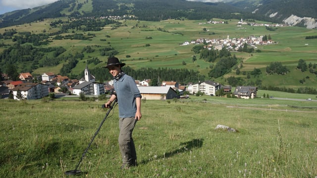 Simon Kurmann, il student da l'Universitad da Turitg examinescha il terren sur Cunter cun in detectur da metal.
