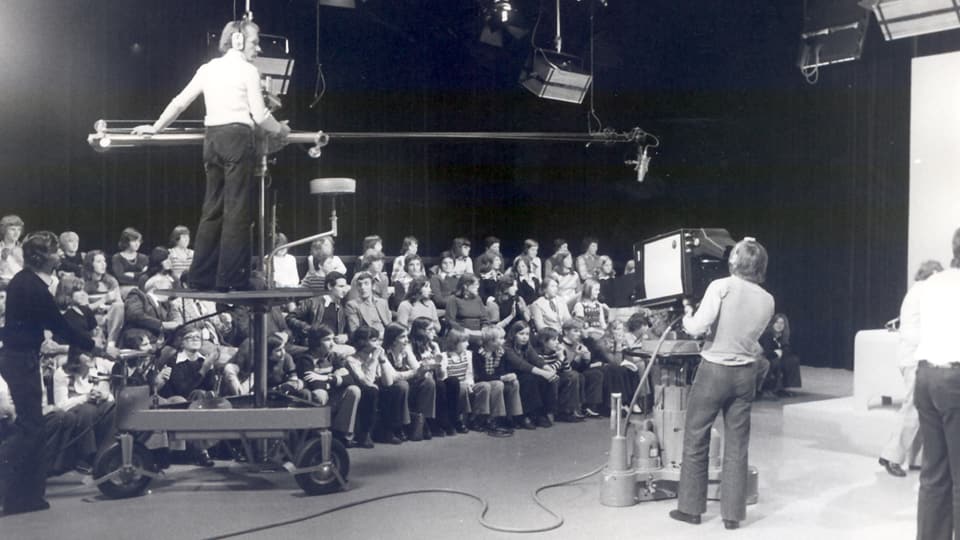 Ums da camera che filmeschan il public d'ina emissiun da televisiun.