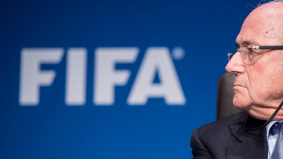 Sepp Blatter che guarda da la vart en. Davossiers  il logo da la FIFA.