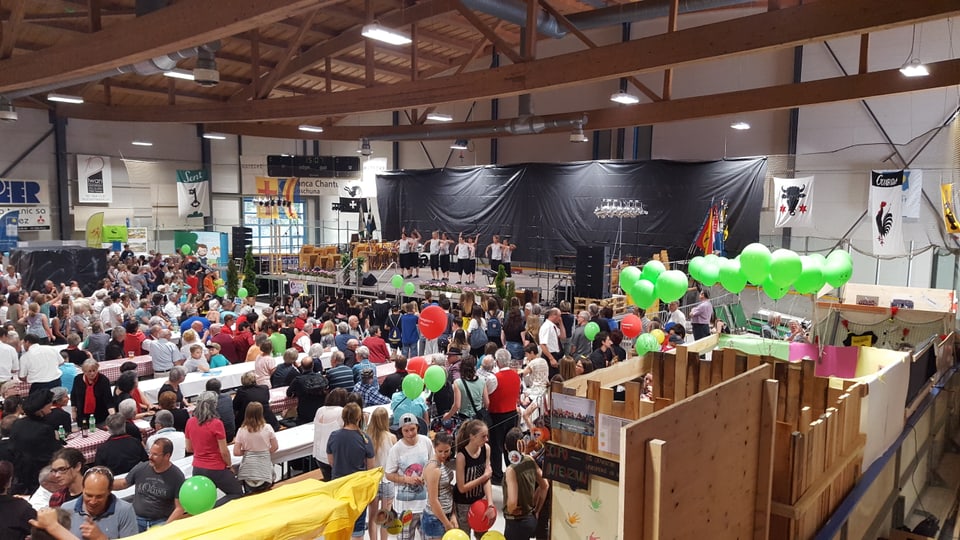 La festa d'inauguraziun da la bandiera nova a Scuol. ina gruppa da saut sin tribuna e aspectaturs.