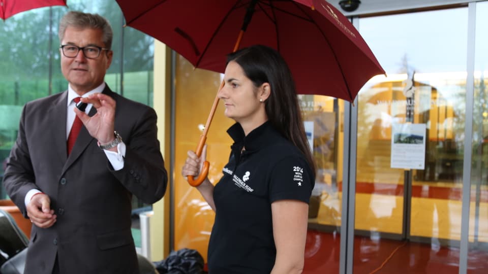 La campiunessa mundiala da curling Binia Feltscher tegn il parasol per il directur da l'hotel.
