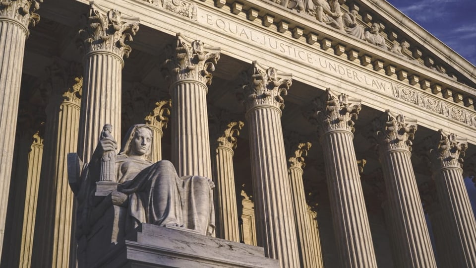 avant las portas dal supreme court cun statua e bajetg en furma da tempel cun stelas