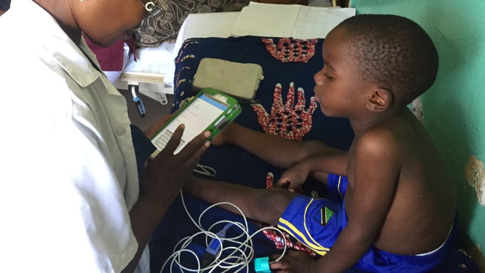 Dr. Samaka dal Ifakara Health Institute, examinescha in uffant cun il e-POCT.