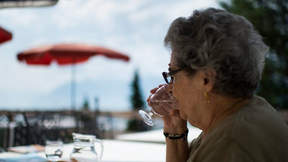 Ina dunna veglia che sesa suletta vid ina maisa e baiva in glas aua. 