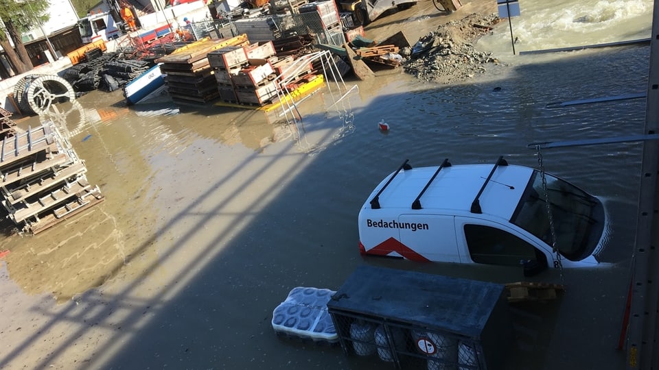 Ins vesa in areal da fatschenta cun material da bajegiar ed autos. Il terren è inundà.