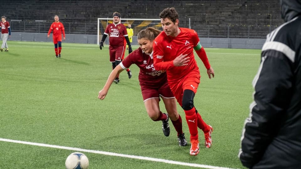 Cumbattì vegn per mintga balla – Giuanna Caviezel vom CB Rumantschia und Lars Guggisberg, der Kapitän des FC Nationalrat kämpfen um den Ball.