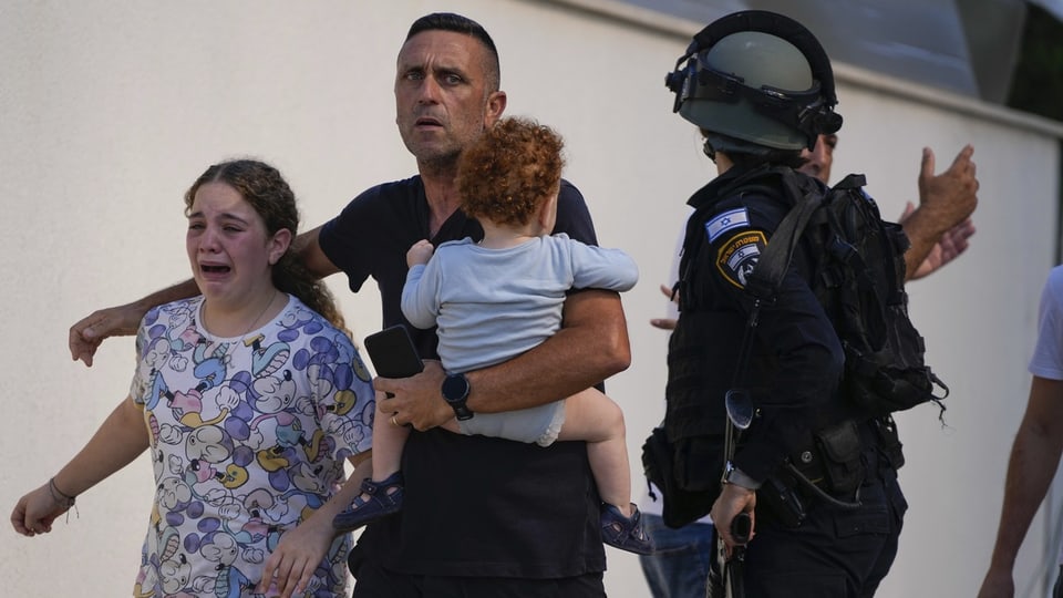 Israelische Polizeibeamte evakuieren eine Familie von einem Ort, der von einer Rakete der Hamas getroffen wurde