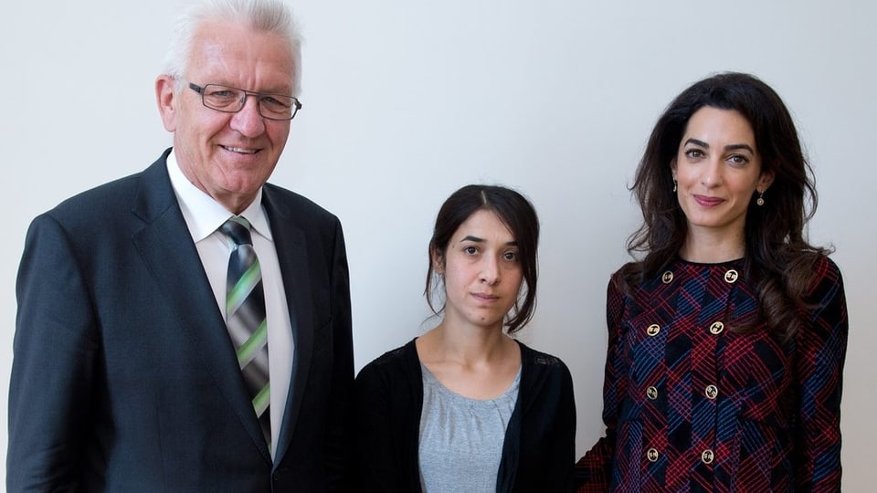 Nadia Murad (mez) a chaschun d’in inscunter a Stuttgart cun Winfried Kretschmann ed Amal Clooney.