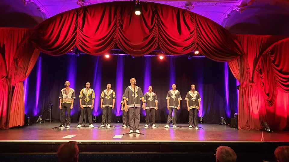 Ladysmith Black Mambazo - 8 umens en vestids nairs cun detagls africans chantan en in mez rintg.