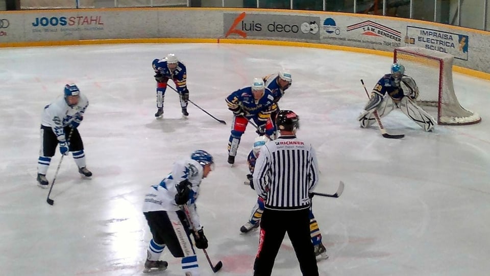 Giugaders da hockey ed in arbiter en acziun.