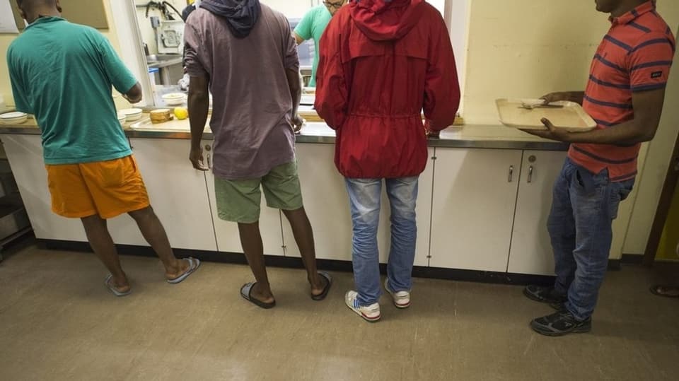 Immigrants che spetgan avant ina cantina sin lur damagliar