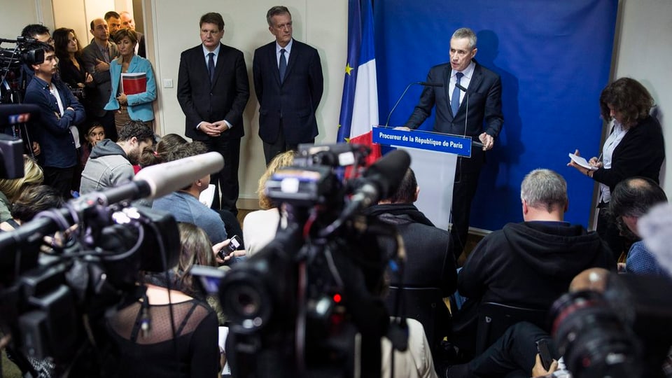 Il procuratur public Francois Molins è circumdà da schurnalists durant la conferenza da pressa en connex cun las attatgas da terror a Paris