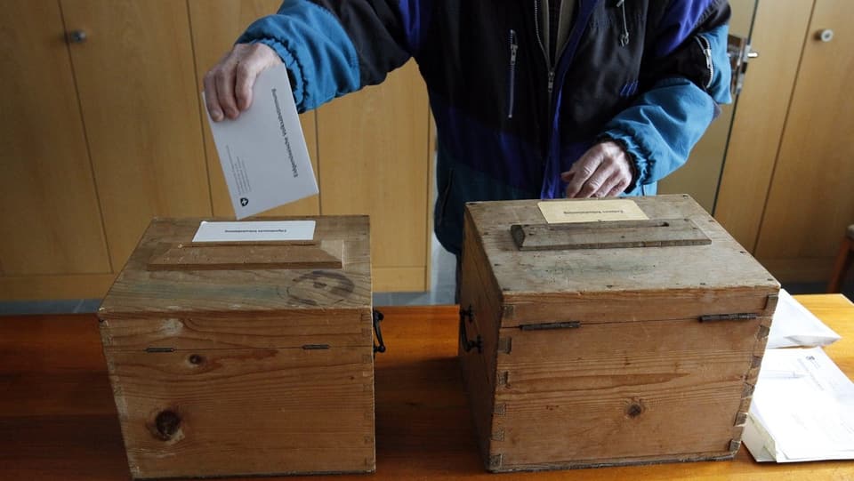duas urnas per votar, ina persuna metta ses cedel en l'urna
