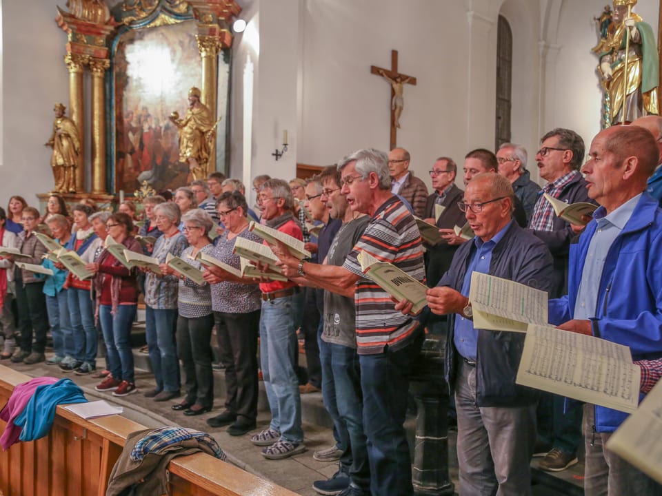 Umans e dunnas chantan en la baselgia da Glion. 