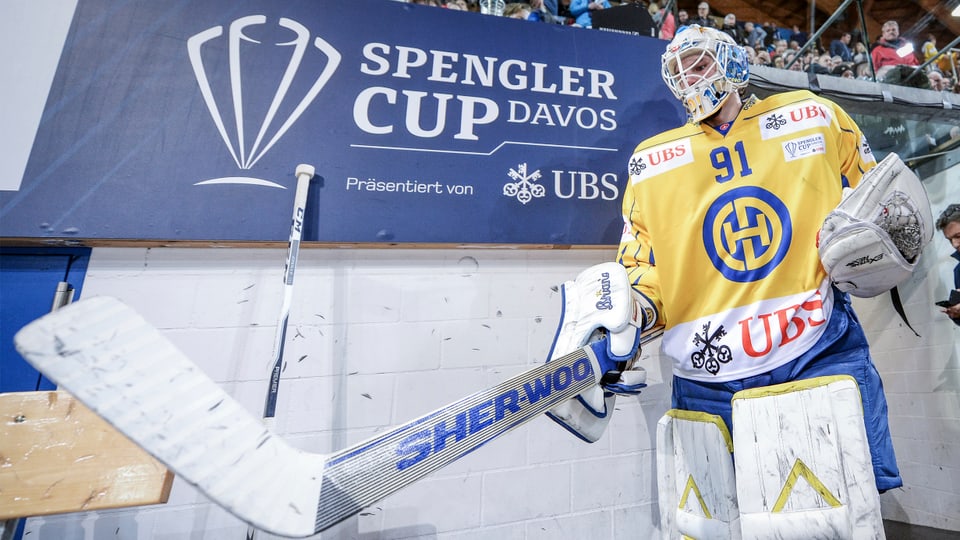 Purtret d'in giugader dal HCD davant il logo da la Cuppa Spengler. 