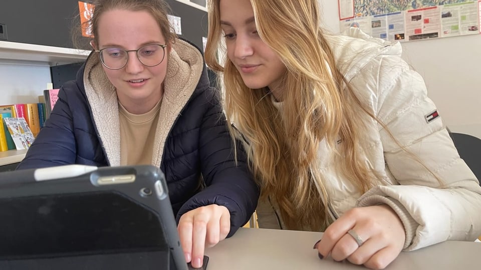 Zwei junge Frauen geben einen interessierten Blick in ein iPad.