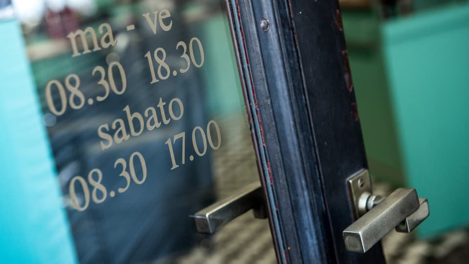 Ina porta blaua d'ina buttia en il tessin cun scrit si ils temps d'avertura.