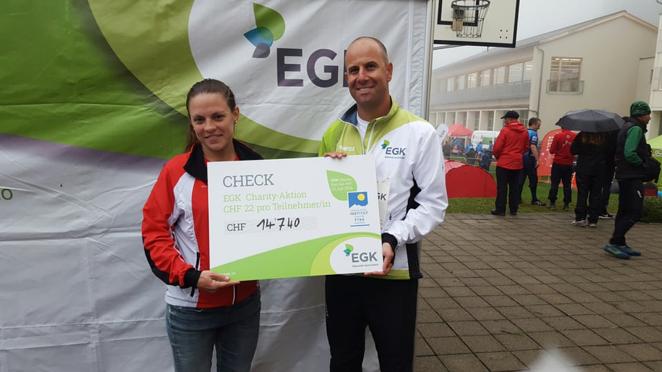 Muriel Hüberli, manadra classa da sport e Reto Flury, manader da gestiun EGK tar la surdada dal check.