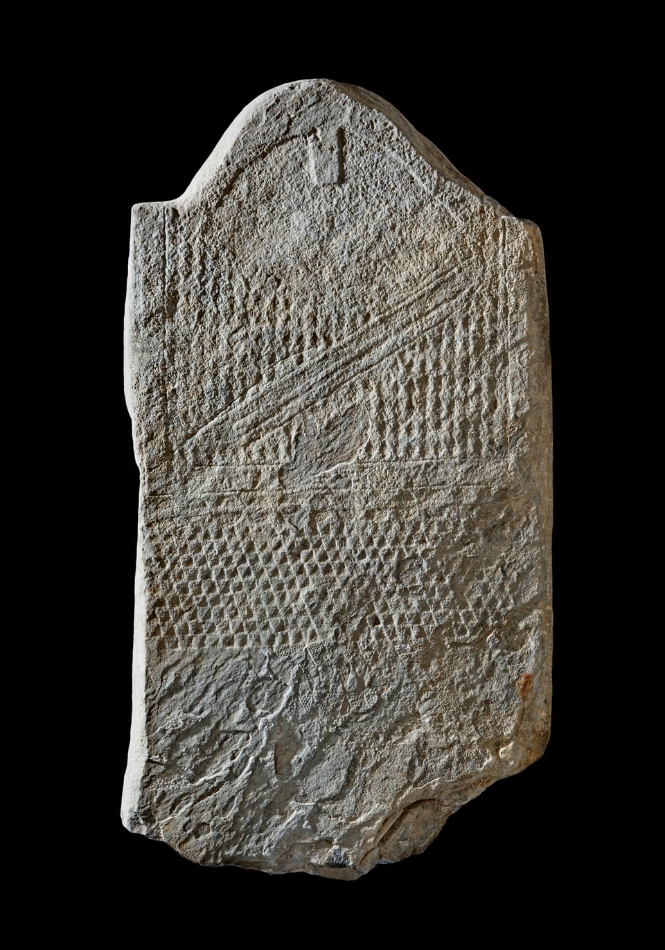 Stela masculina cun fatscha en furma da t, vestgì cun musters, frizza e balester. Marmel. 