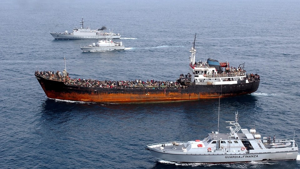 Ina bartga cun fugitivs accumpignada da bartgas da la guardia taliana.
