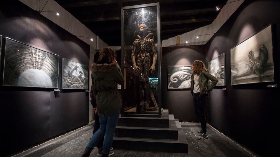 Visitaders che guardan sin ina sculptura da H.R. Giger
