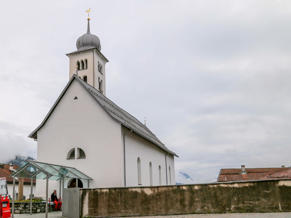 La baselgia refurmada da Castrisch cun ses tipic tetg da vaider a l'entrada.