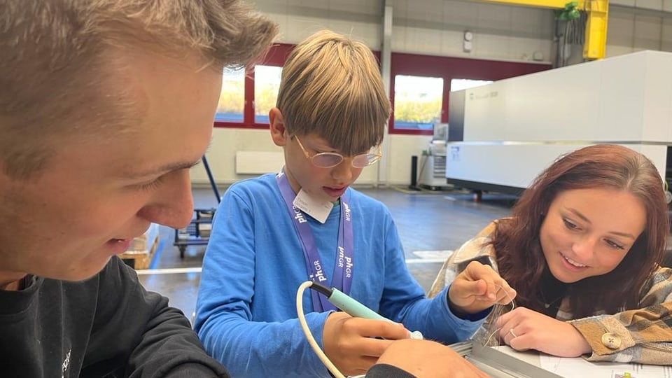 Ein Lehrling der Firma Trumpf und eine Studentin der pädagogischen Hochschule Graubünden, unterstützen einen Schüler