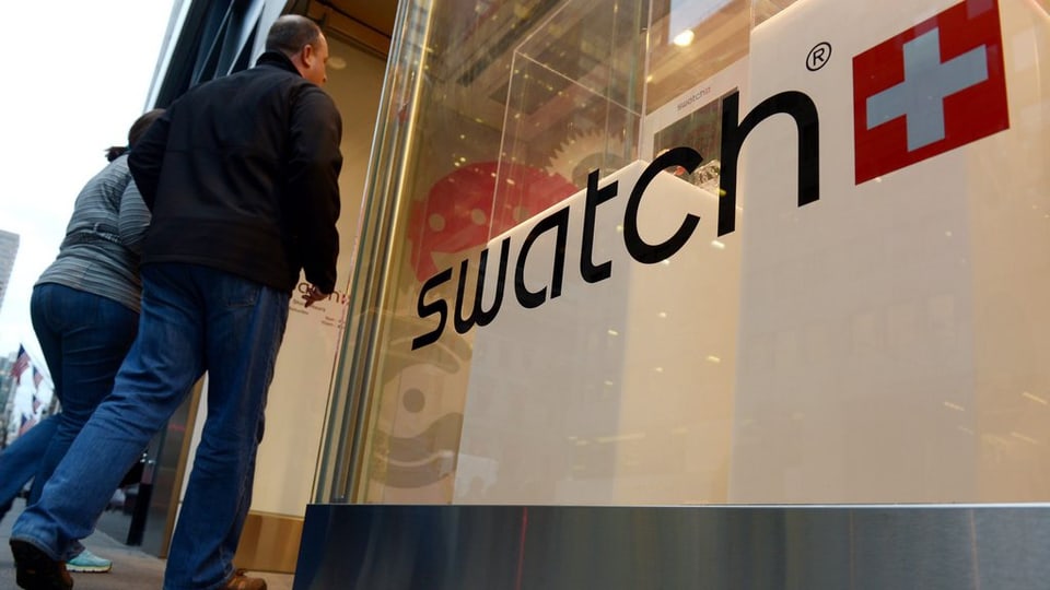 Duas persunas entran en ina stizun dad uras da Swatch.