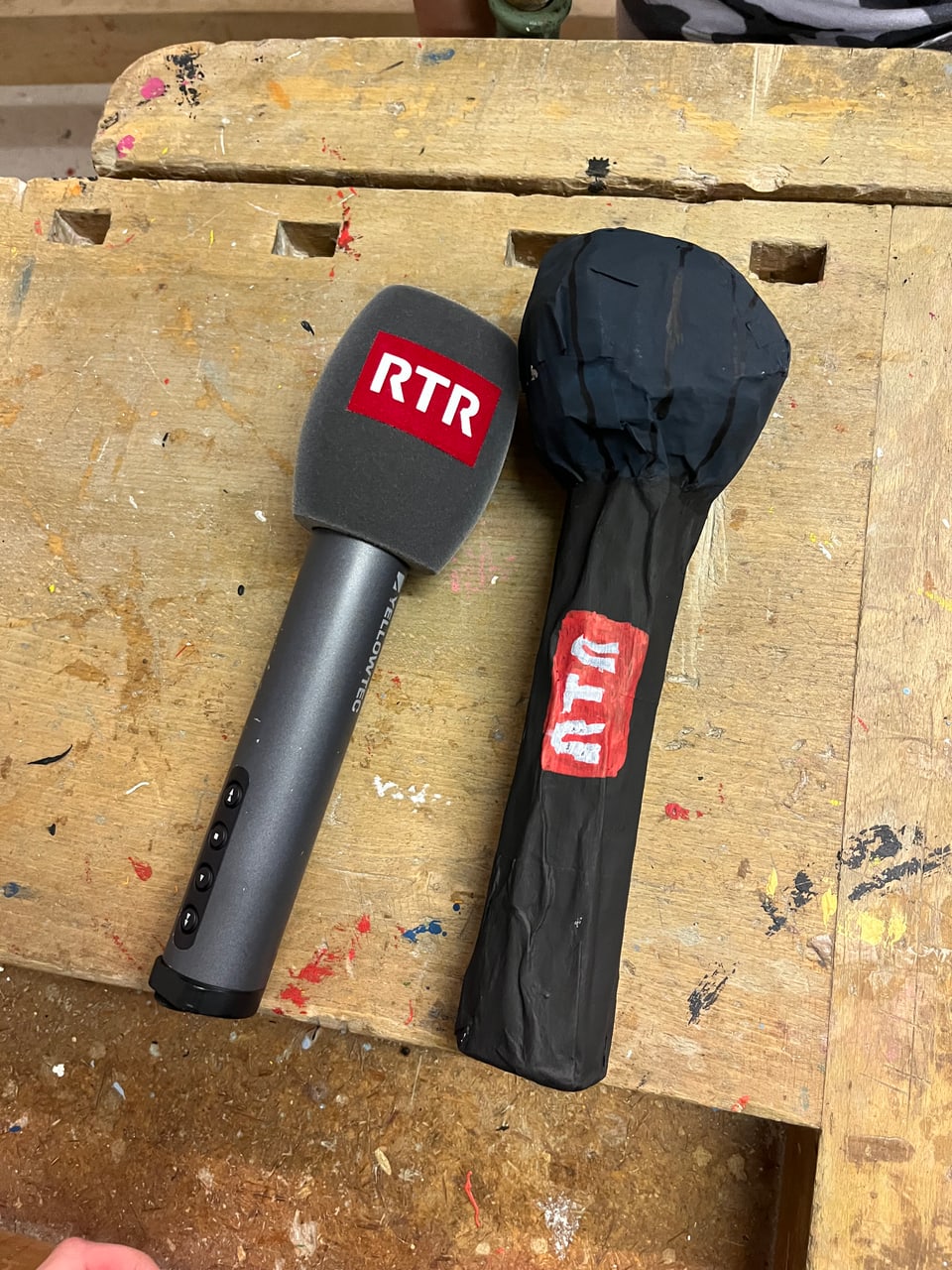 Ein echtes Mikrofon mit dem Logo von RTR liegt neben einem gebastelten.