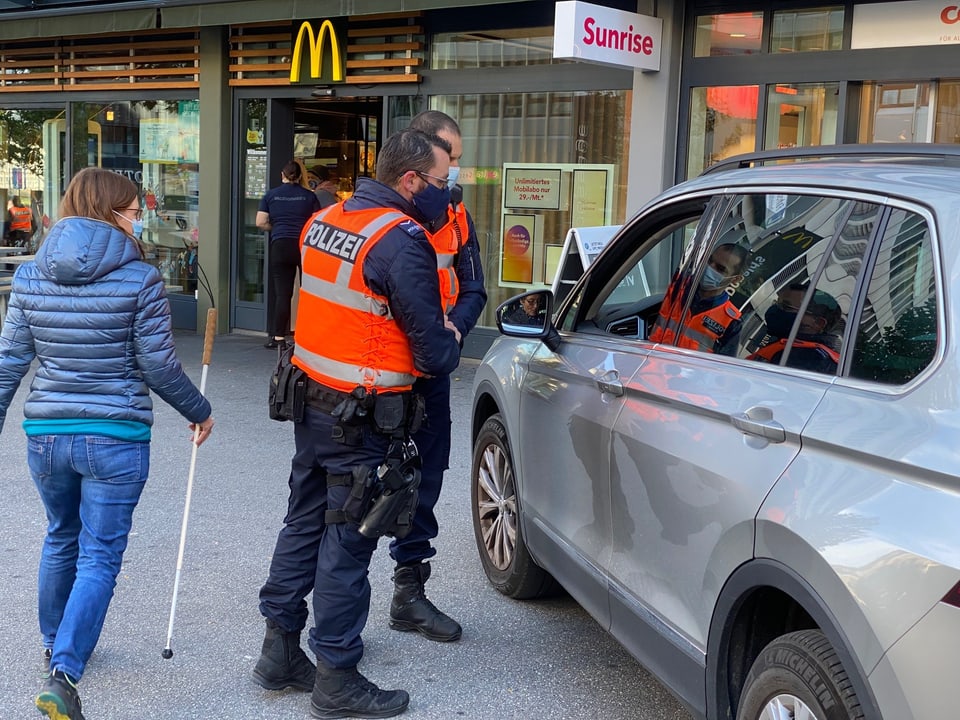 auto cun dasper dus polizists che discurran cun la automobilista, dunna cun channa alva vegn vitiers