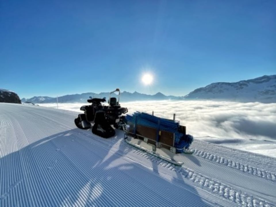 Ina maschina da preparar pistas, cun in magnific panorama.