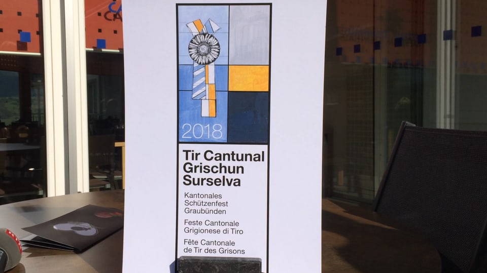 Il logo mussa il Chardunet d'argient (Silberdistel) cun bindels en la colurs grisch mellen e blau sco il vopna dal chantun Grischun. 