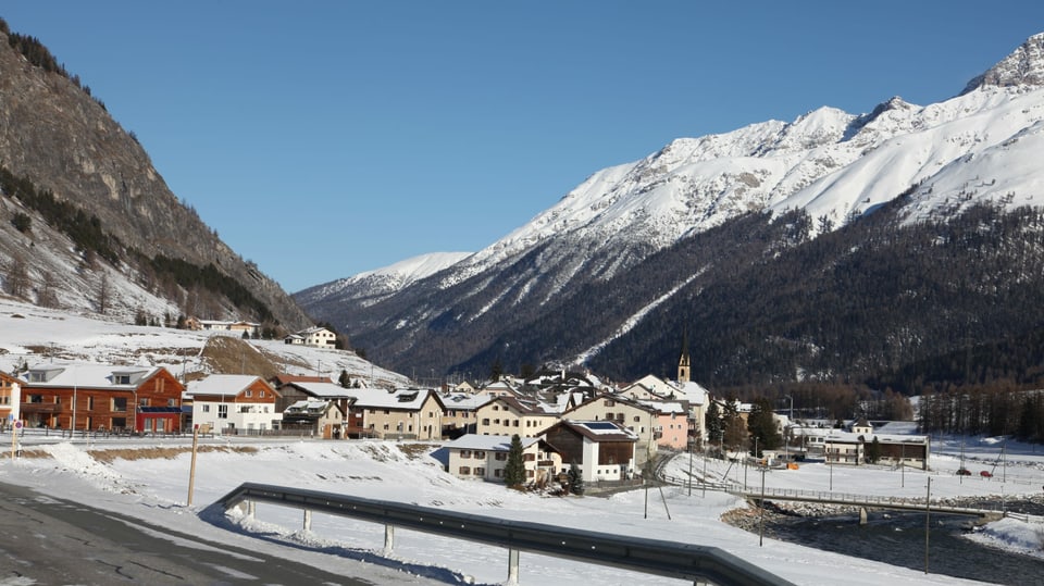 Vista sin S-chanf l'enviern, davant la via che fa ina cura, davos il vitg enramà da las muntagnas.