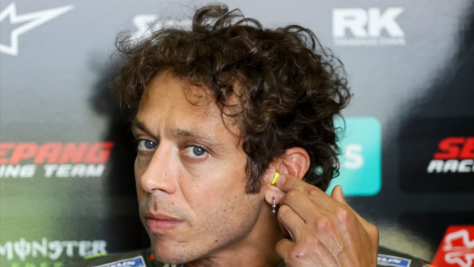 purtret da Valentino Rossi avant ina cursa. In Talian cun egls blaus e chavels da rollas.