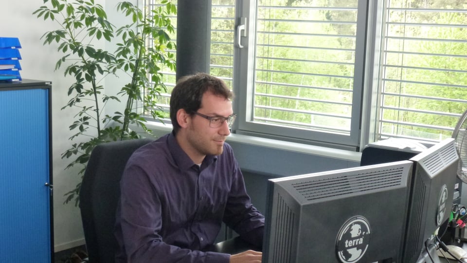 Curdin Tuor en ses biro, che lavura vid in computer.