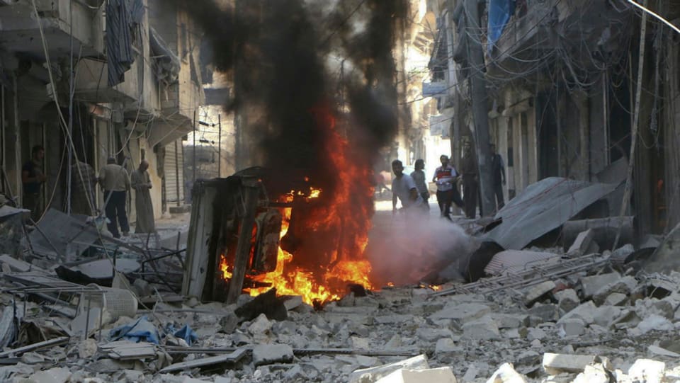 Destrucziun totala ad Aleppo suenter in'attatga ord l'aria. In auto stat en flommas amez las ruinas.