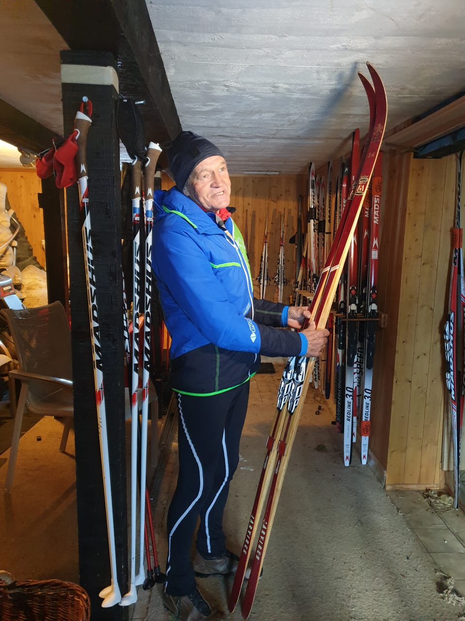 Um pli vegl cun resti da sport che stat sin pes e mussa in pèr skis da lain. 