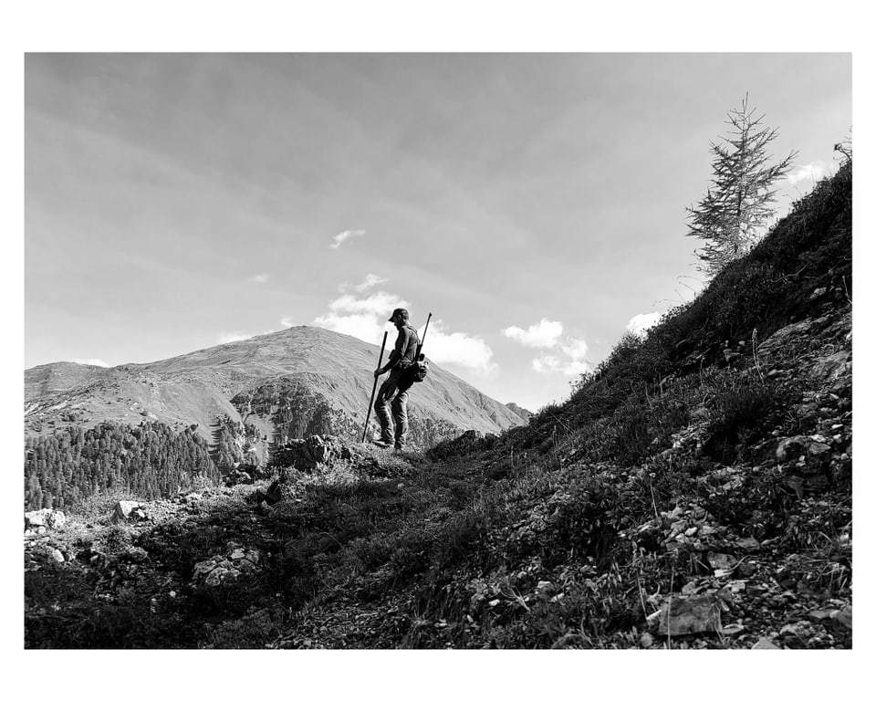 Jäger in Schwarzweiss vor Bergkulisse