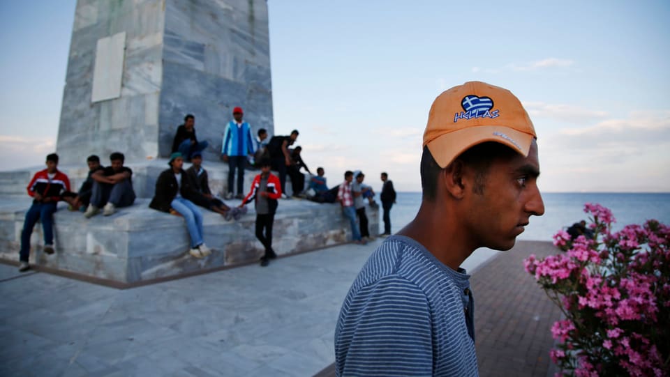 Migrants en il port da Mytilini sin l'insla greca Lesbos guardan suenter ad in bastiment che parta.