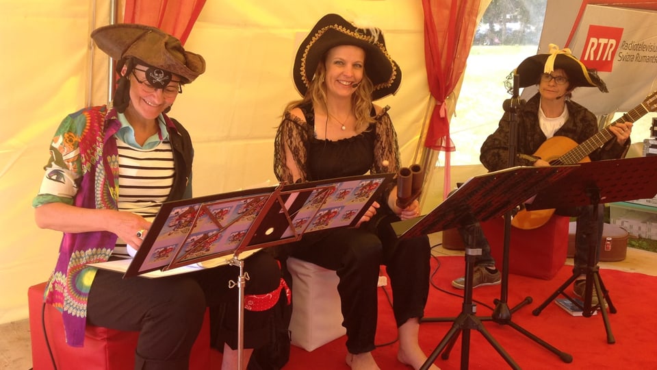 La ghitarrista Jacinta Jacomet cun las raquintadras Sandra Carisch e Marionna Lombriser.