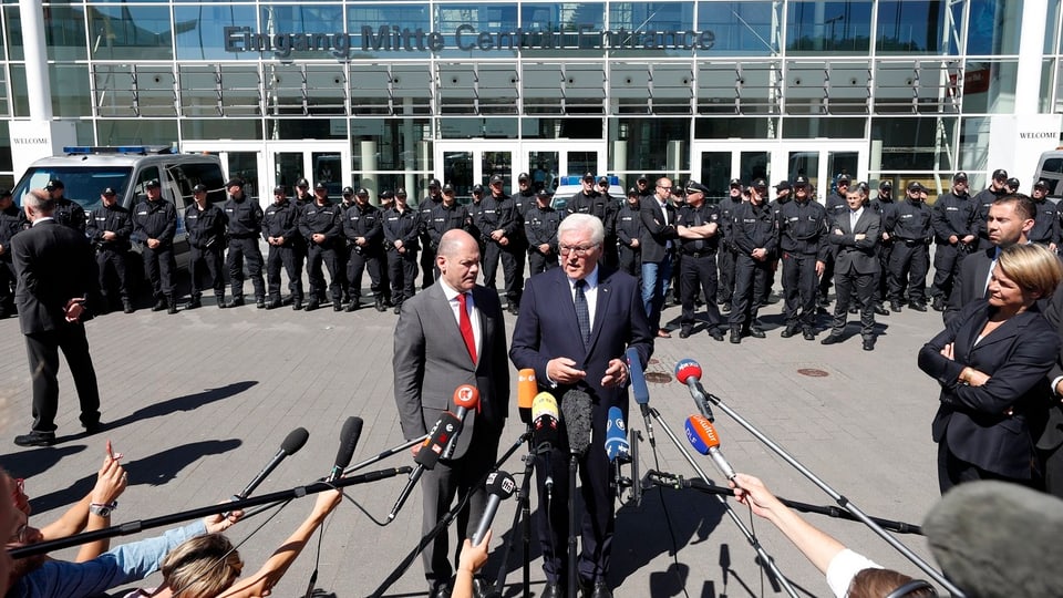 Els dus discurran avant ils policists.
